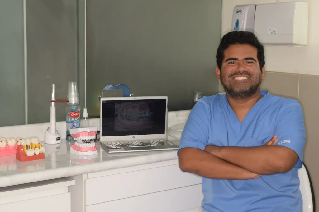 Odontólogo sentado al lado de laptop en clínica dental en Lima Arte y sonrisas